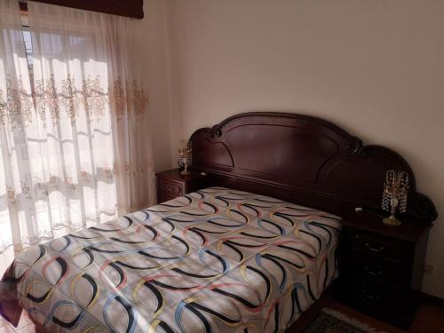 1 dormitorio con 1 cama con cabecero de madera y ventana en Blue Tex en Vila Chã
