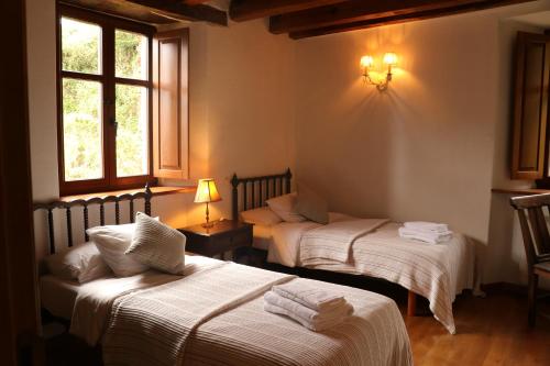 two beds in a room with two windows at Casa Rural Norita - Adults only in Lourenzá