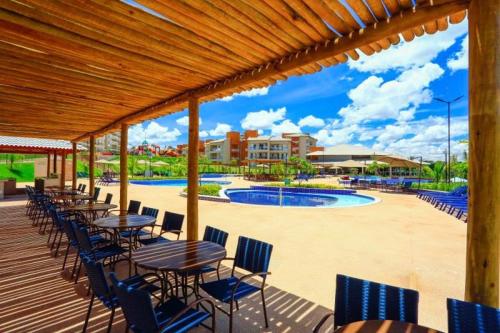 um deque com mesas e cadeiras junto a uma piscina em ILHAS DO LAGO ECO RESORT em Caldas Novas