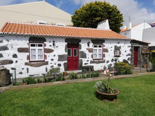 ein weißes Steinhaus mit einer roten Tür in der Unterkunft Fisherman's House Azores in Angra do Heroísmo
