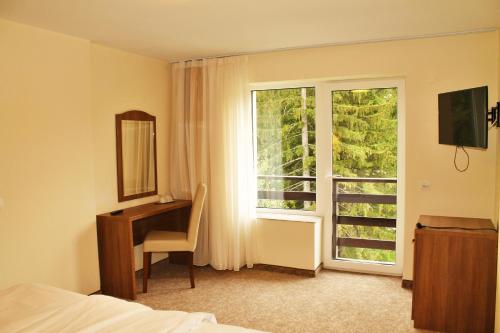 a hotel room with a desk and a window at Hotel Crisalpin in Poiana Brasov