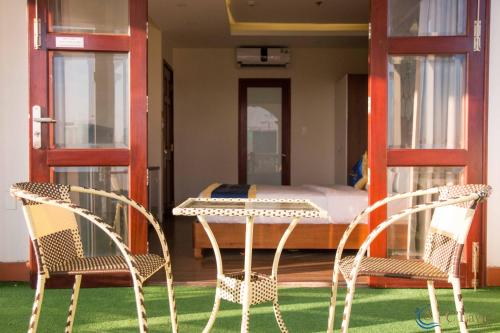 duas cadeiras e uma mesa num quarto com uma cama em C'Lavie Hotel - Saigon Airport Hotel em Ho Chi Minh