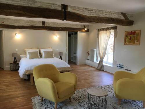 a bedroom with a bed and a couch and chairs at L'evidence in Bragny-sur-Saône