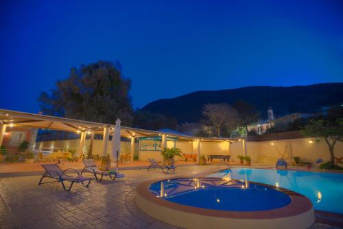 a patio with a swimming pool at night at Santalas Villa in Ágios Matthaíos