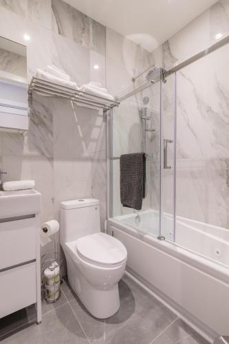 a white bathroom with a toilet and a bath tub at Parc Avenue Lofts in Montréal