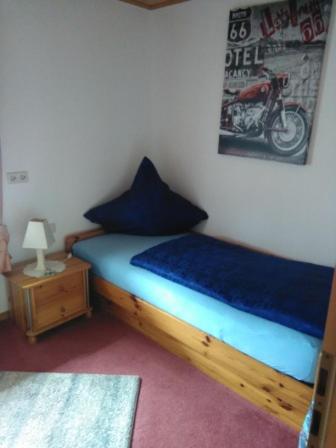 ein Schlafzimmer mit einem Bett mit blauer Bettwäsche und einem Motorrad an der Wand in der Unterkunft Ferienwohnung Hops in Daisendorf
