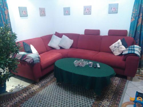 ein rotes Sofa im Wohnzimmer mit einem Tisch in der Unterkunft Ferienwohnung Hops in Daisendorf