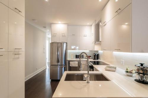 a kitchen with white cabinets and a stainless steel refrigerator at Parc Avenue Lofts in Montréal