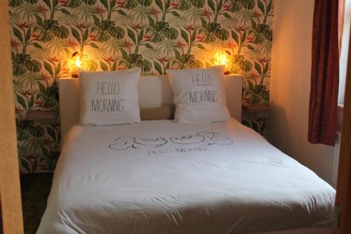 a bed in a room with two pillows on it at L'enjo'Leuze in Winée