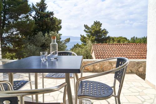 a table with two glasses and a bottle on a patio at STARA GAVZA - bungalows , apartments in Cres