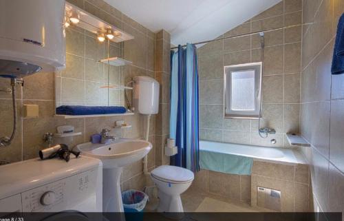 uma casa de banho com um lavatório, um WC e uma banheira em Apartmani Asanović em Budva