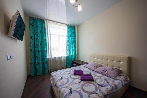 a bedroom with a bed with purple pillows and a window at Апартаменты на Ленинской от ApartmentCity in Mogilev