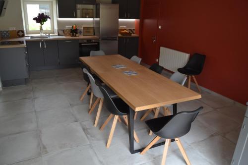 une cuisine avec une table en bois et des chaises noires dans l'établissement Gîte de la Foye - Le magnolia, à Combrand