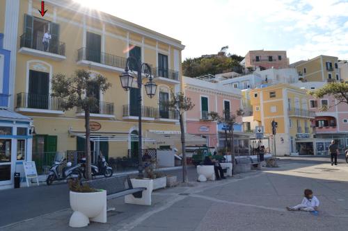 a girl sitting on the ground in a street with buildings at Maridea - Appartamenti Via Dante in Ponza