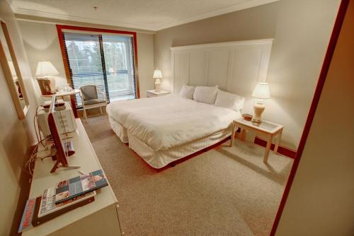 Un dormitorio con una gran cama blanca y una ventana en Greystone Lodge en Whistler