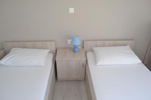 two beds in a room with a night stand with a lamp at Skunca’s house in Novalja