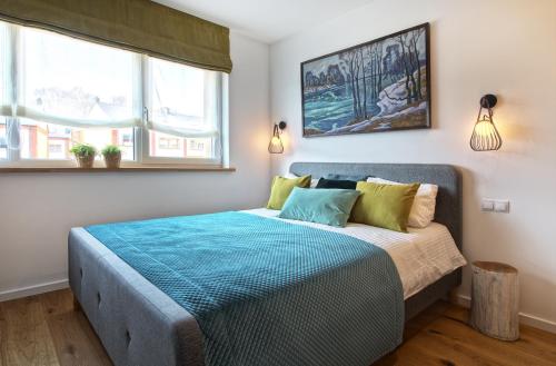 una camera da letto con un letto con lenzuola blu e due finestre di Brand new modern townhouse a Vilnius