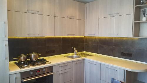 a kitchen with white cabinets and a sink and a stove at Gardino Apartamentai in Šiauliai