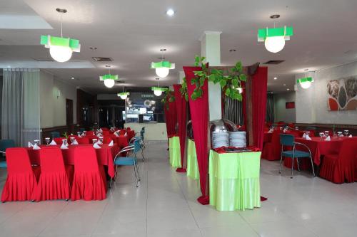 a restaurant with red and green tables and chairs at Super OYO 742 Mona Plaza Hotel in Pekanbaru