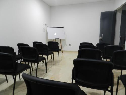 an empty room with black chairs and a white wall at Hotel Bolivariana Plaza Medellin in Medellín