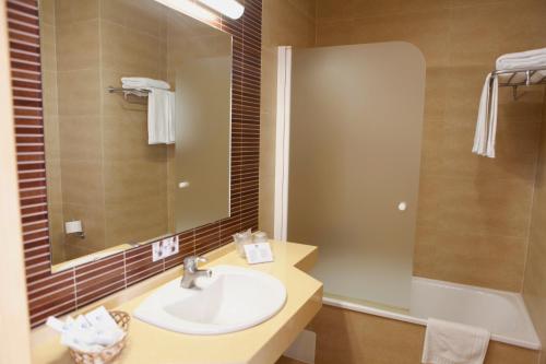 a bathroom with a sink and a mirror and a tub at Hotel Adiafa in Barbate