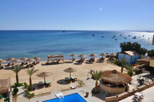 a beach with umbrellas and chairs and the ocean at Dolphin Hotel Safaga in Safaga 
