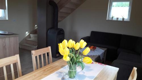 a vase of yellow flowers on a table in a living room at Domki pod Derkaczem in Wünschelburg