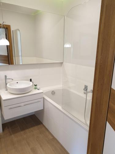 biała łazienka z umywalką i prysznicem w obiekcie Apartament Starowiejska w mieście Gdynia
