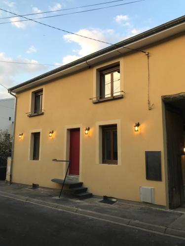 a yellow building with a red door on a street at Hôtel La Bonaventure Jezainville in Jezainville