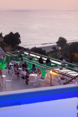 a group of people sitting around a swimming pool next to the ocean at Sunny Hill Alya Hotel in Alanya