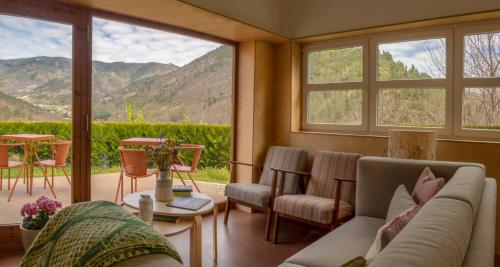 a living room with a couch and tables and windows at Solar da Castanha - Forest House in Manteigas