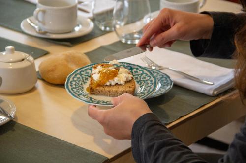 a person eating a piece of bread on a table at Solar da Castanha - Forest House in Manteigas