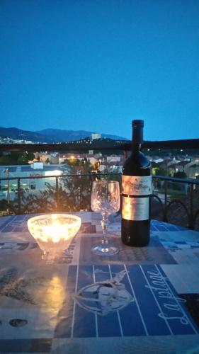 una botella de vino sentada en una mesa con dos copas en Apartman Petra en Senj