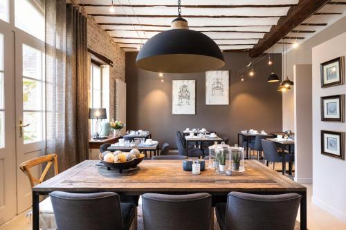 une salle à manger avec une grande table et des chaises en bois dans l'établissement Hôtel Le Clos du Colombier 1817 Vignes & Spa, à Pommard