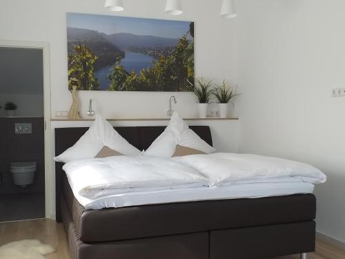 uma cama com lençóis brancos e almofadas num quarto em York Cottage Heaven em Traben-Trarbach