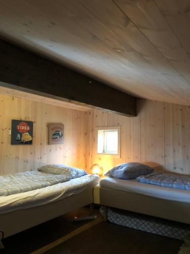 two beds in a room with wooden walls at Kuvågen 29 in Bøvågen