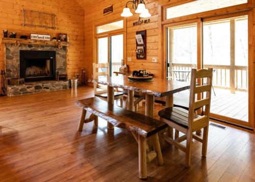 a dining room with a wooden table and a fireplace at stayNantahala - Smoky Mountain Cabins in Aquone