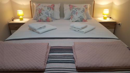 a bed with two pillows on it with two lamps at Boka View in Igalo