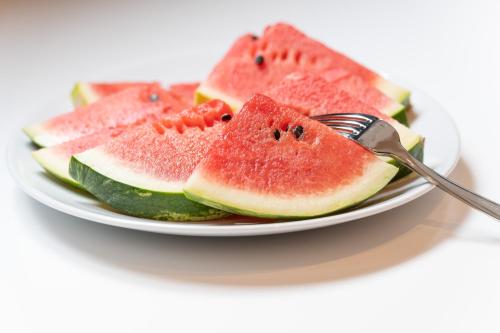 a plate of watermelon slices on a plate with a fork at Boutique Hotel Sablon by CW Hotel Collection in Bruges