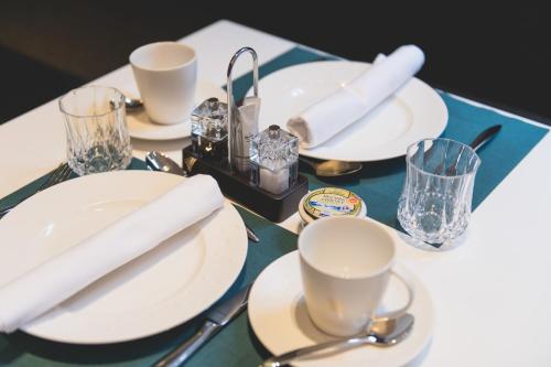 a table topped with white plates and cups and silverware at Boutique Hotel Sablon by CW Hotel Collection in Bruges