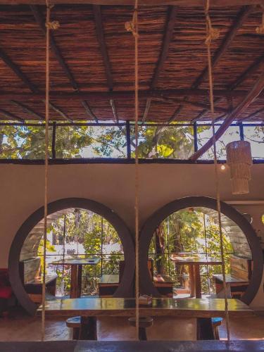 a porch with tables and swings in a building at Hostal Mulut Tulum in Tulum