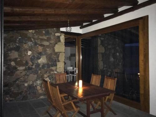 a wooden table and chairs in a room with a stone wall at Casa de Los Alberconcillos in Agüimes