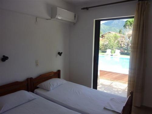 two beds in a bedroom with a view of a pool at Stathis Apartments in Dassia