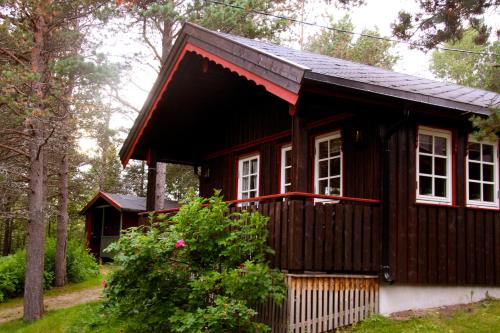 a house with a wooden roof and a wooden bench at Fauske Camping & Motel in Fauske