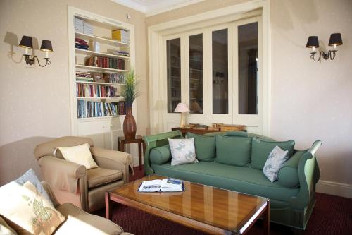 a living room with a green couch and a table at The Lodge On The Loch Onich in Onich
