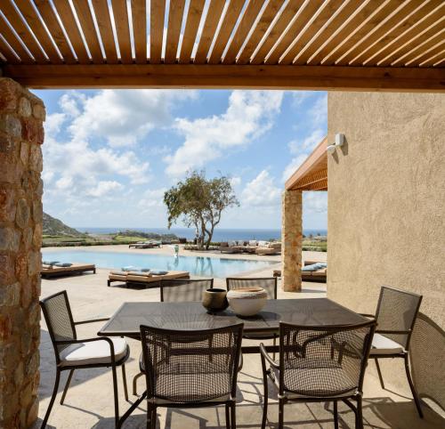 een patio met een tafel en stoelen en een zwembad bij Cellaria Estate Exclusive in Vlychada