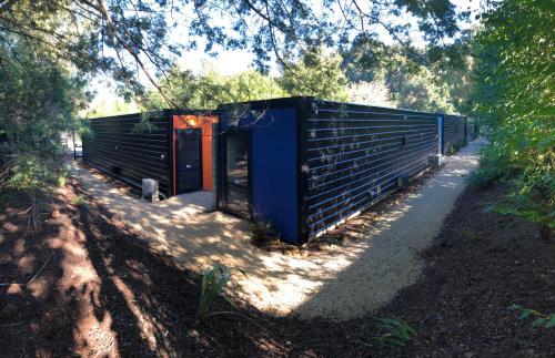 a black and orange building in the shade of trees at Adventure Inn Marahau in Marahau