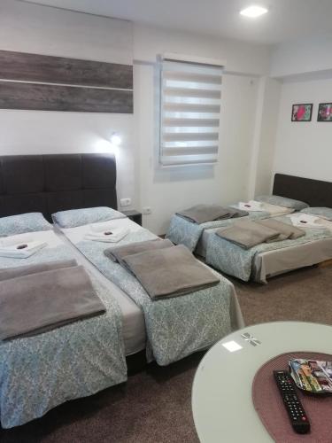 een kamer met drie bedden en een tafel erin bij Apartman Centar 1 in Užice