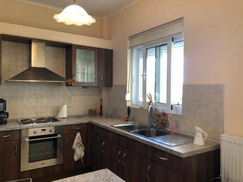 a kitchen with wooden cabinets and a sink and a window at Renting House GALINI in Plakias