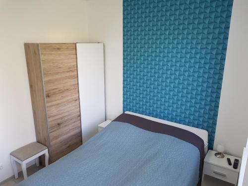 a small bedroom with a bed and a blue wall at Lakefive Apartments Balatonfüred in Balatonfüred